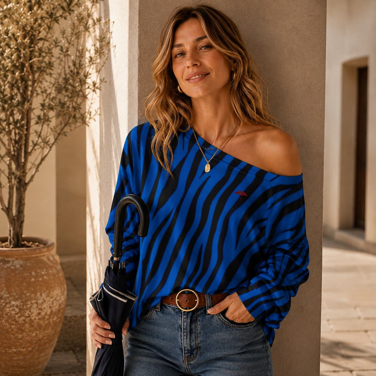 Sweat-shirt à manches longues et épaules dénudées pour femme porte de face une mains dans la poche l'autre tenant un parapluie couleur bleu